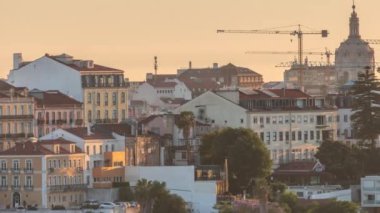 Gün batımında Lizbon 'un merkezindeki tepedeki renkli evlerin hava manzarası. Estrela bazilikası kilisesi ve çalışan vinçler. Bakış açısına göre insanlar. Portekiz