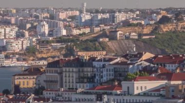 Lizbon şehrinin Bairro alto bölgesinin kırmızı çatılarından gün batımında Tejo nehrinin sol kıyısındaki Almada belediyesine genel bakış. Portekiz