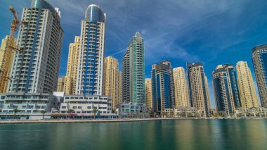 Dubai Marina Kuleleri, Birleşik Arap Emirlikleri 'ndeki gezinti güvertesi zaman aşımından suya yansıdı. Dubai Marina, Dubai 'de yer alan bir şehirdir. Mavi bulutlu gökyüzü