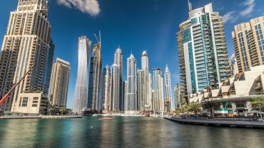 Dubai Marina modern yüksek kuleleri, Birleşik Arap Emirlikleri 'ndeki gezinti zamanı aşırı hızından dolayı suya yansıdı. Dubai 'de bir bölge ve yapay bir kanal. Mavi bulutlu gökyüzü