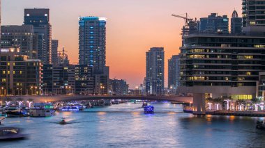 Dubai Marina rıhtımı, Dubai 'deki köprüden gece vardiyasına kadar uzanan kuleleri ve yatları olan Birleşik Arap Emirlikleri. Gün batımından sonra yapay kanallı bölge