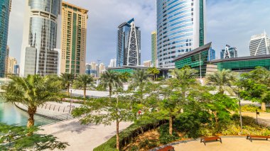 Rıhtımdaki palmiyeli gökdelenlerin hızlandırılmış görüntüsü. Jumeirah Lake Towers semtinde camla kaplı konut binaları Dubai, BAE 'de suya yansıdı. Rıhtımdan görüntüle