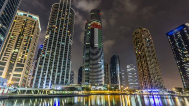 Rıhtımdaki ışıklandırılmış gökdelenlerin gece görüş açısını hızlandırın. Dubai, BAE 'deki Jumeirah Gölü Kuleleri' ndeki konut binaları. Rıhtımdan görüntüle