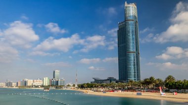 Abu Dabi marinasının şehir manzarası İran Körfezi, BAE 'de plajı olan hiperhızlandırılmış zaman çizelgesi. Abu Dabi, Birleşik Arap Emirlikleri 'nin başkenti ve en kalabalık ikinci şehridir. Mavi bulutlu gökyüzü