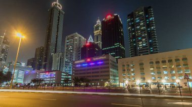 Dubai Kuleleri 'nin aşağısında gece vakti aşırı hızlanma. Şeyh Zayed 'in yüksek gökdelenli manzarası. Yoldaki trafik ve çok katlı otopark. Yanıp sönen ışıklar ve patikalar