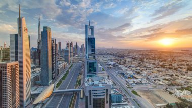 Dubai gökdelenleri, gün batımı akşam vakti. Dubai metro istasyonu ve Şeyh Zayed Yolu 'ndaki trafik. Kule çatısından gökyüzü görüntüsü. Güzel renkli bulutlu gökyüzü