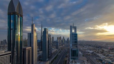 Dubai gökdelenleri akşam saatlerinde güneş camlarında yansıyor. Dubai metro istasyonu ve Şeyh Zayed Yolu 'ndaki trafik. Kule çatısından gökyüzü görüntüsü. Renkli bulutlu gökyüzü ve güneş ışığı