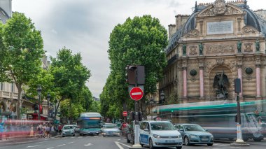 Saint-Michel Meydanı 'nın tarihi çeşmeli sokak manzarası, Paris. Arabalar ve insanlarla kavşakta trafik vardı. Yaz gününde bulutlu bir gökyüzü