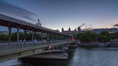 Pont de Bir-Hakeim (formerly pont de Passy) night - a bridge that crosses the Seine River. Central arch decorated with monumental statues. Cars and trains traffic on road. Paris, France clipart