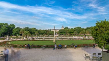 The beautiful view of the Luxembourg Gardens timelapse hyperlapse with fountain in Paris, France. People relaxing on chairs. Blue cloudy sky at summer day. clipart