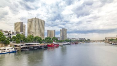 Fransa Ulusal Kütüphanesi, ormanlık bir alanı çevreleyen açık kitap biçimindeki dört binası olan hiperhızlandırılmış zaman dilimi. Tolbiac Köprüsü 'nden Seine Nehri' ne yansıyan hava görüntüsü. Paris, Fransa