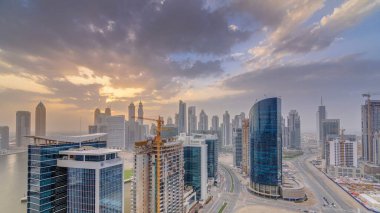 Dubai iş hangarı kuleleri, gün batımında hava zaman tüneli panoramasında. Bazı gökdelenlerin çatı manzarası ve inşaat halindeki yeni kuleler.