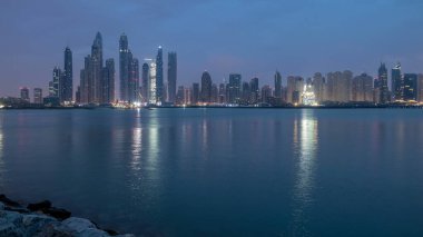 Gün geçiş timelapse Dubai şehir gece Palm Jumeirah Adası'içinde modern gökdelenler Panoraması. Dubai, Birleşik Arap Emirlikleri. Dubai Yat Limanı ve sabah erken bulutlara Jbr