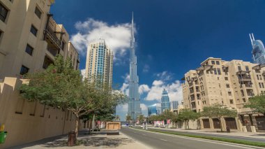 Dubai street timelapse hyperlapse üzerinde yürüme. Konut ve iş gökdelenler merkezinde, yolda trafik. Dubai, Birleşik Arap Emirlikleri. Mavi bulutlu gökyüzü. Avuç içi ve sokakta ağaçlar