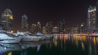 Dubai Yat Limanı defne yatların bir tekne timelapse hyperlapse. Kanal suya yansıyan gece ışıklı gökdelenler