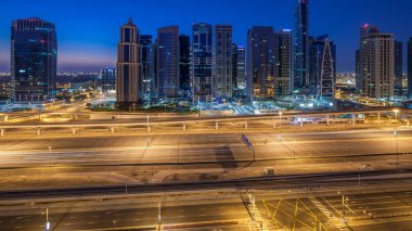 Jumeirah lakes hava görünümünü gün geçiş timelapse Şeyh zayed road ve metro hattı üzerinde trafik ile gecesine ışıklandırılmış gökdelenler ile kuleleri. Dubai Yat Limanı güneş doğmadan önce çatı görünümü