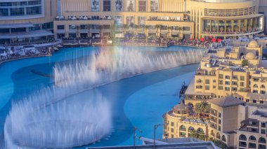 Akşam havası manzaralı şehir merkezinde dans eden fıskiyeler ve gün batımında Dubai, BAE 'de insan yapımı bir göl zamanlamasında..