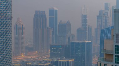 Sisli sabah gün geçiş timelapse gecesine Dubai şehir merkezinde. Şehir gökdelenler fütüristik görünümünü Şeyh zayed yolu üzerinde sis kaplı. Çatı güneş doğmadan önce havadan görünümden. Dubai, Birleşik Arap Emirlikleri