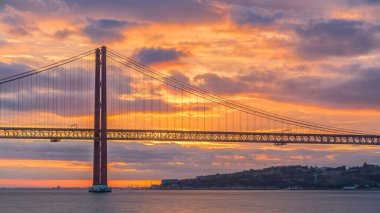 Lisbon city sunrise with April 25 bridge timelapse, River and waterfront early morning. Orange clouds on the sky