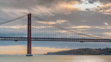 Lisbon city sunrise with April 25 bridge timelapse, River and waterfront early morning. Orange clouds on the sky