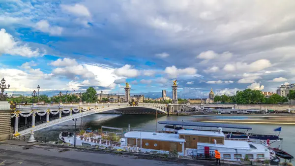 Alexandre III 'ün köprüsü Seine nehrinde hızla ilerliyor. Süslü Art Nouveau lambaları ve heykellerle süslenmiş. Paris mi? Fransa. Tekne ve gemi suda. Gün batımından önce mavi bulutlu gökyüzü