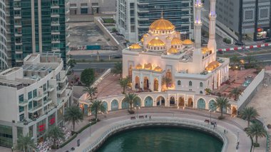 Modern residential architecture of Dubai Marina and Mohammed Bin Ahmed Almulla Mosque aerial day to night transition timelapse, United Arab Emirates. Promenade and traffic on a road clipart