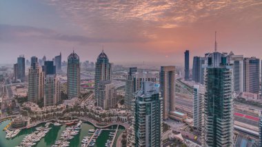 Dubai Marina timelapse gündoğumu havadan üst görünümü. Dubai, Bae yüzen yatlar ve tekneler ile gezinti ve kanal. Modern kuleler ve yolda trafik
