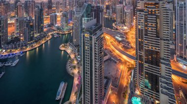 Dubai Marina, Birleşik Arap Emirlikleri 'nde gökdelenleri ve Jumeirah göl kulelerini aydınlatmıştır. Yolda trafik ve yüzen yatlar.