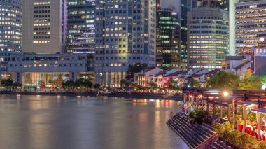 Singapur rıhtımı merkezi iş bölgesinde uzun gökdelenler ve Boat Quay 'de küçük restoranlar gün batımından sonra geçiş zamanı.