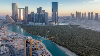 Abu Dabi 'deki Al Reem Adası' ndaki gökdelenler, gün batımından sonra, gece gündüz geçiş zamanları. Al Reem Adası 'ndan aydınlık binaları olan panoramik şehir manzarası.