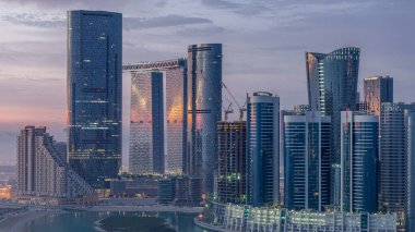 Abu Dabi 'deki Al Reem' deki gökdelenler gün doğumunda gökdelenler. Al Reem Adası 'ndan sabah sisli bir şehir manzarası. Güneş cam yüzeyine yansıyor