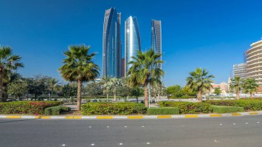 Ebu Dabi 'nin gökdelenleri Etihad Kuleleri' nin binaları zaman atlamalı. Avuç içleriyle ve trafiğiyle park et. Güneş cam yüzeyden yansıyor. Birleşik Arap Emirlikleri