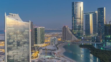 Abu Dabi 'deki Al Reem Adası' ndaki gökdelenler, gün batımından sonra, gece gündüz geçiş zamanları. Aydınlatılmış binaları olan Al Reem Adası 'ndan havadan şehir manzarası
