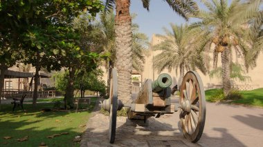 Historic fort at the Museum of Ajman timelapse hyperlapse with blue sky, United Arab Emirates. Old cannon near palm clipart