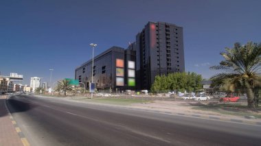 Trafiği yoğun olan Ajman 'ın şehir manzarası. Alışveriş merkezi ve otel panoramik zaman atlaması olan siyah bir bina. Ajman, Birleşik Arap Emirlikleri 'nde Ajman Emirliğinin başkentidir..