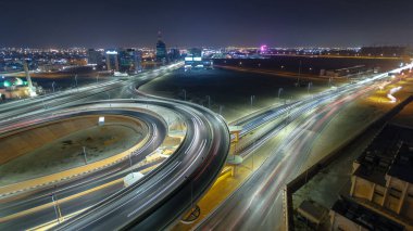 Panorama, Ajman hava sahasında büyük bir kavşakta trafiği gösteriyor. Gece vakti çatıdan görünüyor. Birleşik Arap Emirlikleri 'nde üst geçitle kesişen birçok araba var..