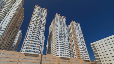 Ajman zaman ayarlı hiperhızlandırılmış modern yeni kuleler. Ajman 'ın yerleşim yeri ve ofis gökdelenleri olan şehir manzarası. Mavi gökyüzü. Birleşik Arap Emirlikleri.
