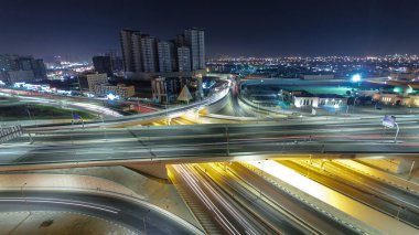 Panorama, Ajman hava sahasında büyük bir kavşakta trafiği gösteriyor. Gece vakti çatıdan görünüyor. Birleşik Arap Emirlikleri 'nde üst geçitle kesişen birçok araba var. Arkaplanda gökdelenler