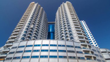 Ajman zaman ayarlı hiperhızlandırılmış gümüş kuleleri olan modern yeni mavi. Ajman 'ın yerleşim yeri ve ofis gökdelenleri olan şehir manzarası. Birleşik Arap Emirlikleri.