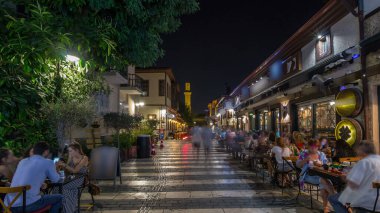 Kaleiçi timelapse hyperlapse Kesik Minare Camii cami Antalya'da kırık Minare üzerinde gece manzaralı tarihi cadde boyunca yürüyüş. Etrafta dolaşan insanlar