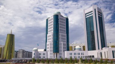 Nur-Sultan şehrinde Kazakistan Cumhuriyeti Senatosu 'nun binaları aşırı hız kazanmıştır. Ön planda çiçek açmış. Arka planda Nurzhol Bulvarı. Yazın mavi bulutlu gökyüzü