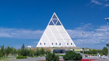 Exterior of the Palace of Peace and Reconciliation building timelapse hyperlapse with park and fountains near by. Kazakhstan, Nur-Sultan city clipart