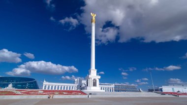 Kazakistan 'ın başkenti Astana' daki Independence Meydanı 'ndaki Kazak Eli Anıtı' nın zaman atlaması görüntüsü. Alttaki çiçek tarhında. Yaz günü mavi bulutlu bir gökyüzü. Nur-Sultan şehri