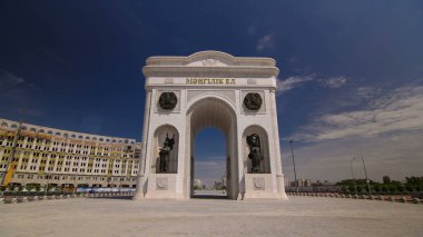 Triumphal arch timelapse with national man and woman statues and the central part of the city with clouds in summer day in Nur-Sultan city, Kazakhstan. clipart