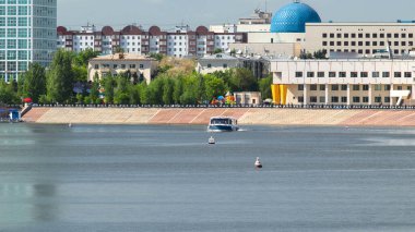 Astana, Kazakistan. Astana 'da Ishim nehrinde hareketli bir eğlence teknesi var. Yazın mavi gökyüzü ve bulutlarla