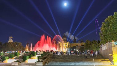 Barcelona 'daki Placa Espanya Ulusal Sanat Müzesi' nin önünde, gece Katalonya, İspanya 'da ünlü ışık gösterisi ve sihirli çeşmeler hızlanıyor. Gökyüzünde dolunay görünüyor