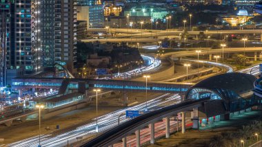 Futuristik binada Dubai metro ve tramvay istasyonu ve lüks gökdelenler arkasında gece timelapse içinde Dubai Marina, Birleşik Arap Emirlikleri. Hava üst görünümden Jlt trafik ile Şeyh zayed yolu üzerinde