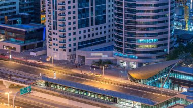 Dubai Yat Limanı gökdelenler ve tramvay istasyonu hava üstten görünüm güneş doğmadan önce Jlt gelen Dubai gece gün timelapse, Birleşik Arap Emirlikleri için. Işıklı modern kuleleri ve Şeyh zayed yolu üzerinde trafik.