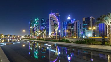 Geceleri Doha 'nın ufuk çizgisi. Yıldızlı gökyüzü Park Timelapse hiper hızından görünüyor, Katar. Aydınlatılmış gökdelenler ve kuleler çeşme suyuna yansıyor