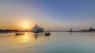Katar 'ın Doha kentindeki İslam Sanatları Müzesi yakınlarındaki günbatımında, arkasında yükselen gökdelenler görülüyor. Öndeki eski tekneler.